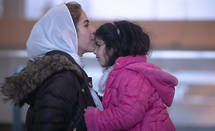 woman in headscarf kisses toddler on the forehead