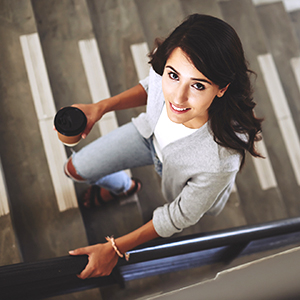 woman walks up stairs with coffee cup