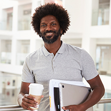 man with beard holds tablet, coffee