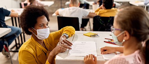 teacher in a face mask works with pupil in a face mask