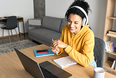 woman wearing headphones studies with laptop
