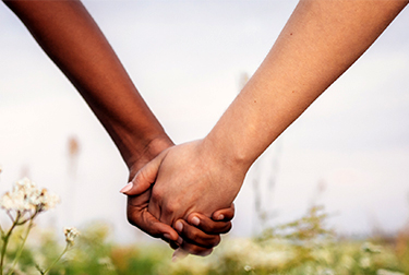 multi-ethnic couple holding hands in a field