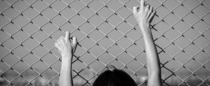 child holding onto chain link fence