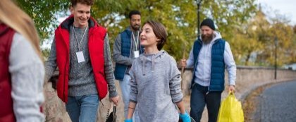 kids and adults walking by river with picked up trash
