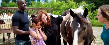 girl with her mother looking at a horse