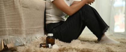 woman sitting by pill bottles