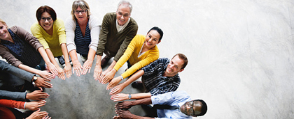 group of people in a circle, hands pointing to the center