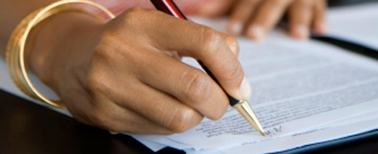 hand with pen writing on document