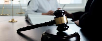 gavel in foreground, two people sit at table in background