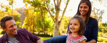 a man, a woman, a child smiling outdoors