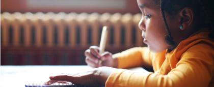 young child writing at a desk