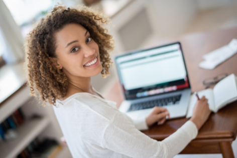 young woman at laptop smiles over her shoulder