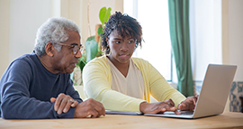 young woman helping male senior citizen with computer