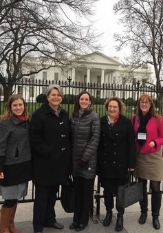 five people stand in front of gate at the White House