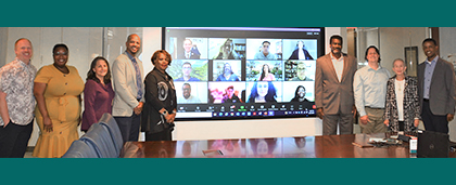 board members posed in a row, including multiple faces on TV screen