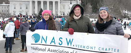 group of people standing at a rally with a large NASW banner