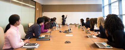 people sitting at a table looking at a presenter