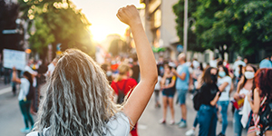 person with raised fist in a crowded street