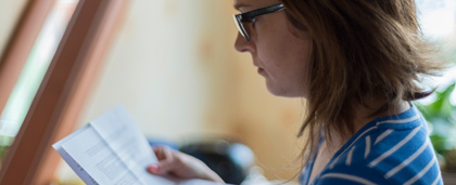 woman in glasses reads a document