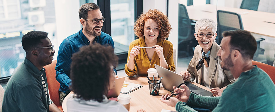 adults converse around a table in an office setting