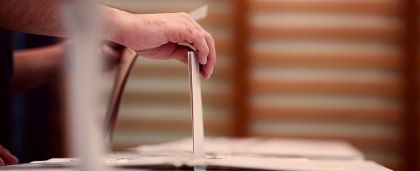 person placing a ballot in a box