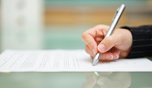 hand signs a paper using a pen