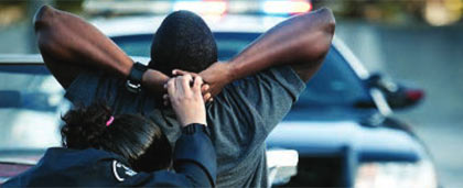 black man's arms pulled back by police officer