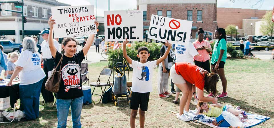 mother and son hold protest signs at rally and volunteers register people to vote.