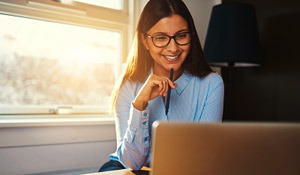smiling woman looks at laptop