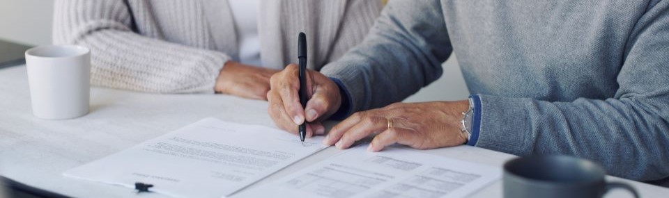 person holding a pen filling out paperwork