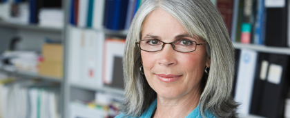 woman stands in front of bookshelf