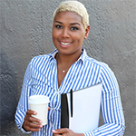 young woman stands with coffee cup and notebook