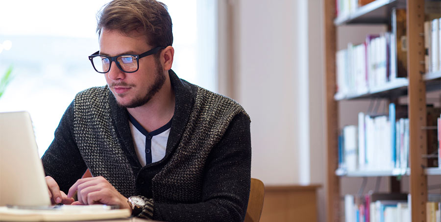 man sits at a table working on a laptop