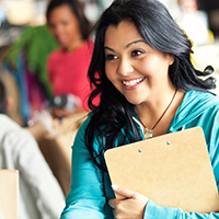 smiling woman with clipboard reaching out to shake someone's hand