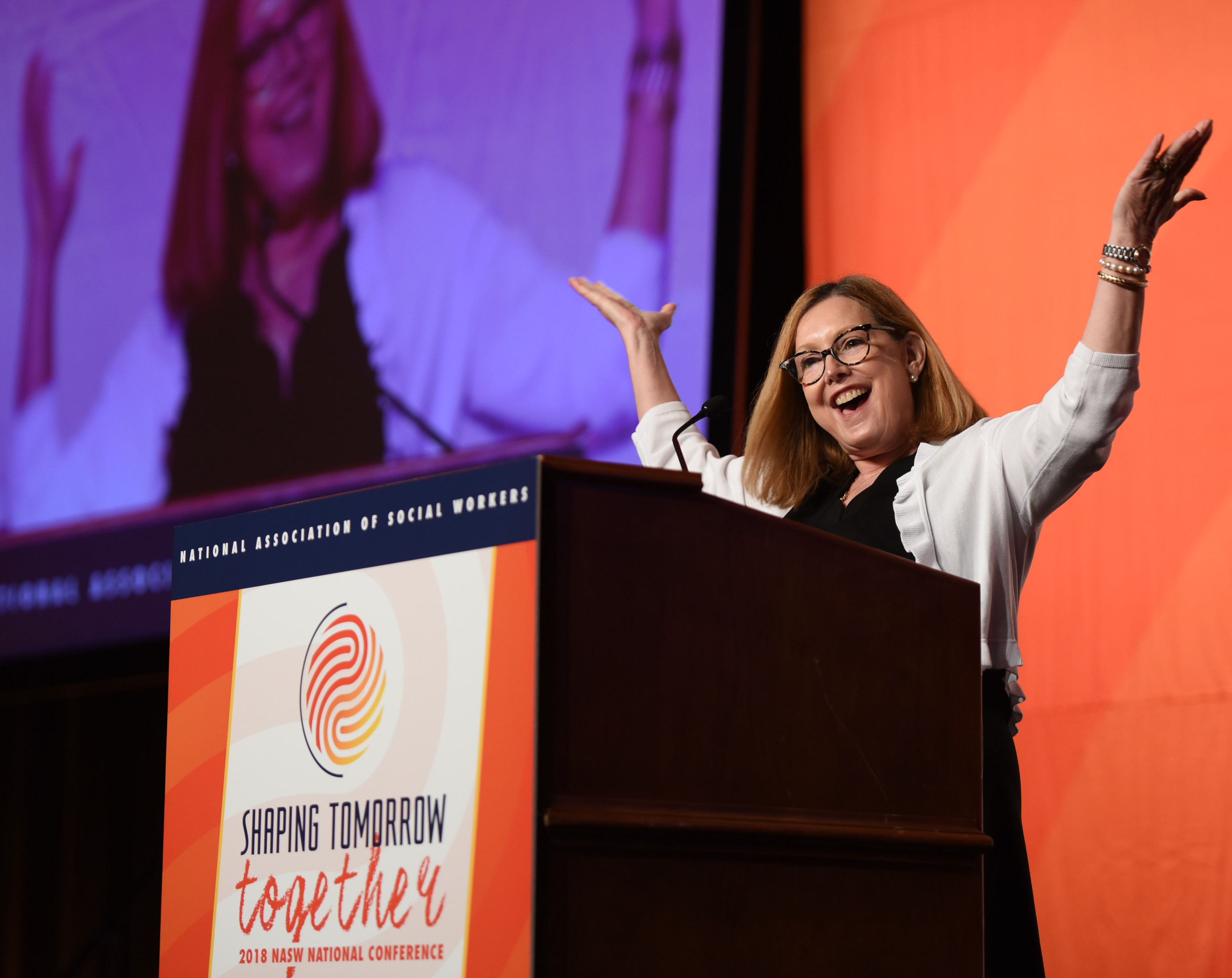 NASW President Kathryn Wehrmann on stage with arms raised