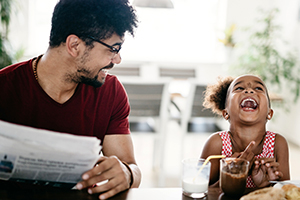 father and daughter laugh during breakfast