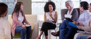 woman speaking to a group of people with notebooks