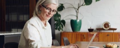 woman looking at notes while typing on laptop