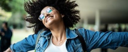 woman smiling with her eyes closed and arms wide