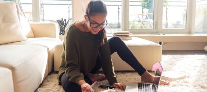 Woman sitting on floor with laptop of documents in front of her