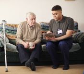 young man helps older man with tablet