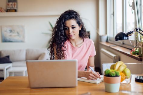 young woman at laptop taking notes