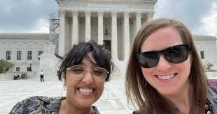 2 students smiling while standing in front of supreme court building