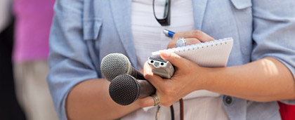 woman with notebook, pens, and microphone in her hands