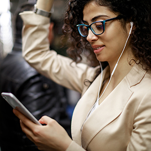 woman on subway wearing headphones looks at her cell phone