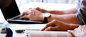 hands of two people, with laptop and book