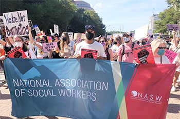 people wearing face masks carrying NASW banner at a march