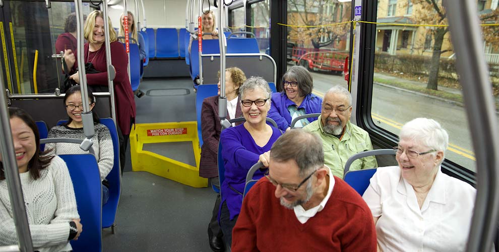 people sit inside a city bus, some young, some older