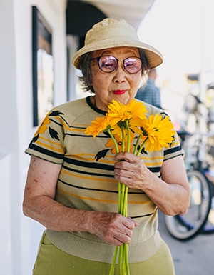 older woman holds bright yellow flowers