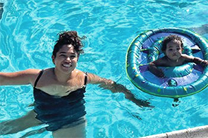 woman in swimming pool with toddler in a floating ring